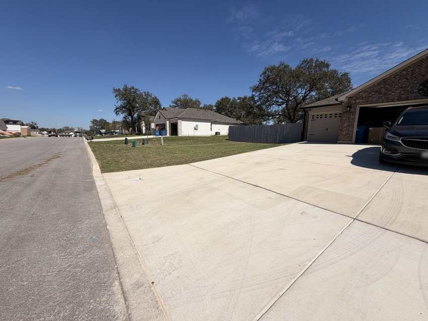 Large finished concrete driveway at a brick home